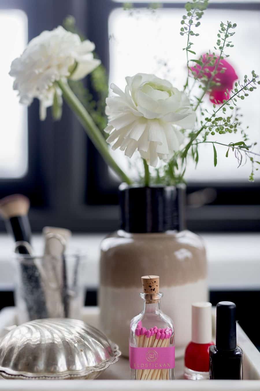 rožiniai dekoratyviniai degtukai interjere su nagų laku ir gėlėmis